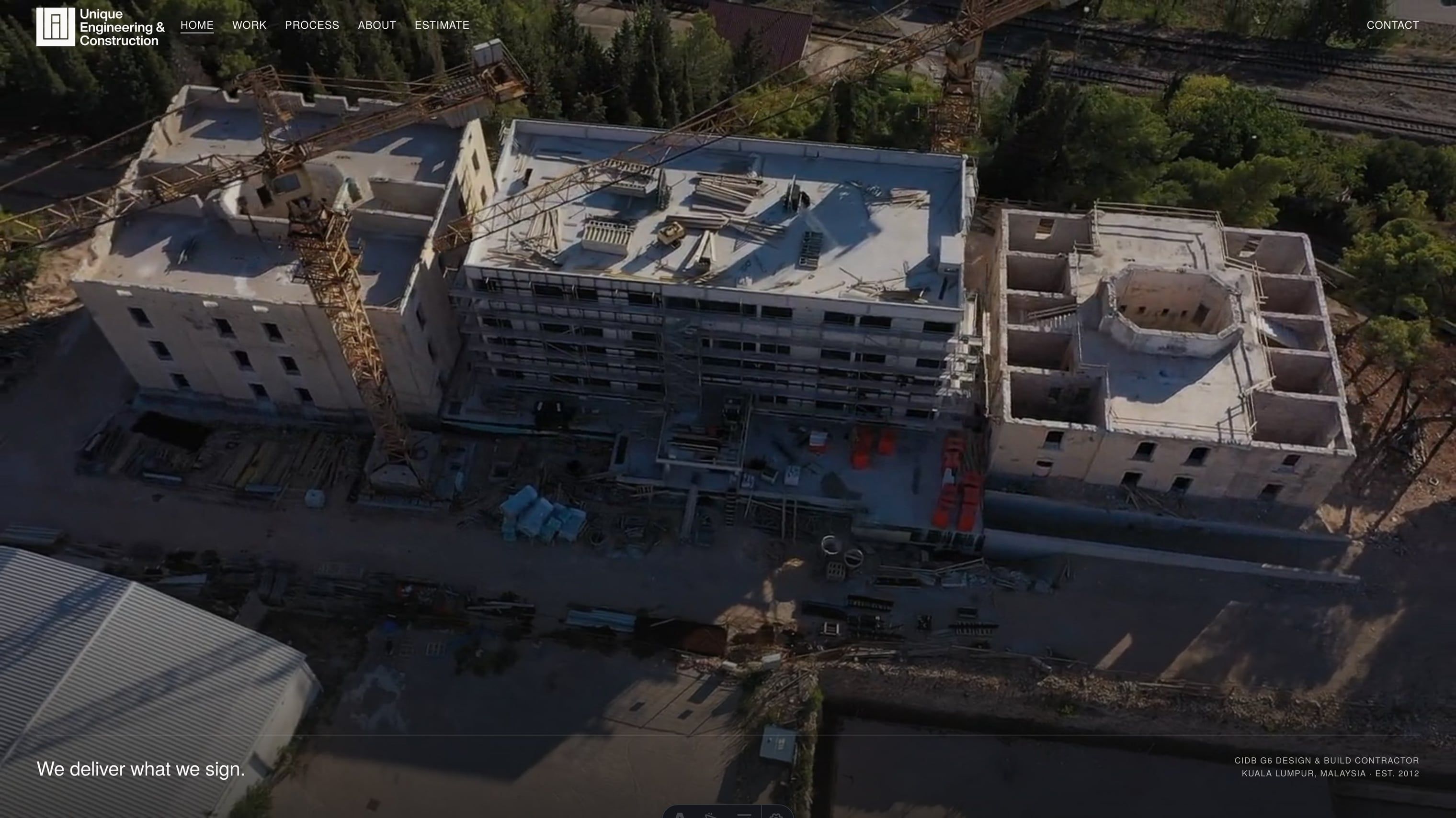 The UEC homepage hero: an aerial video of a high-rise site under the line 'We deliver what we sign.'